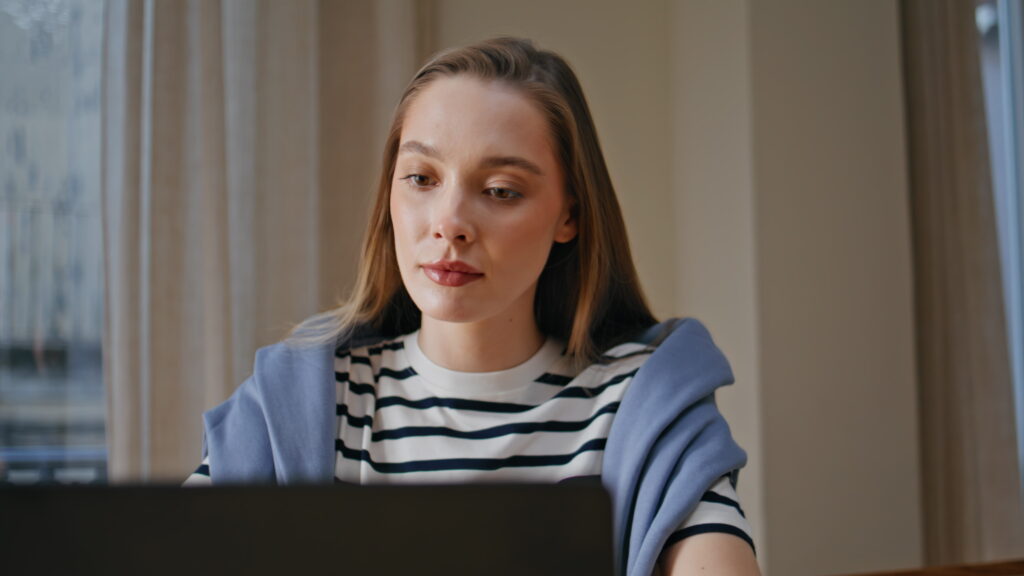 A young woman searching for recent graduate jobs on her laptop with a focused expression.