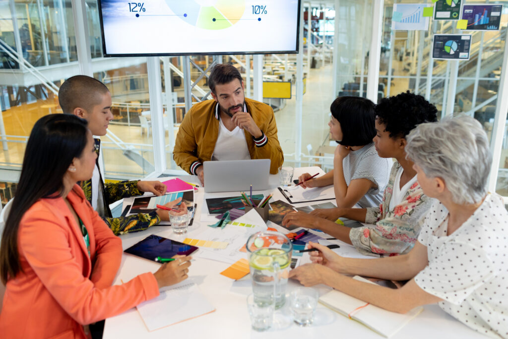 Team collaborating around a table with charts and ideas, demonstrating essential marketing skills in action.